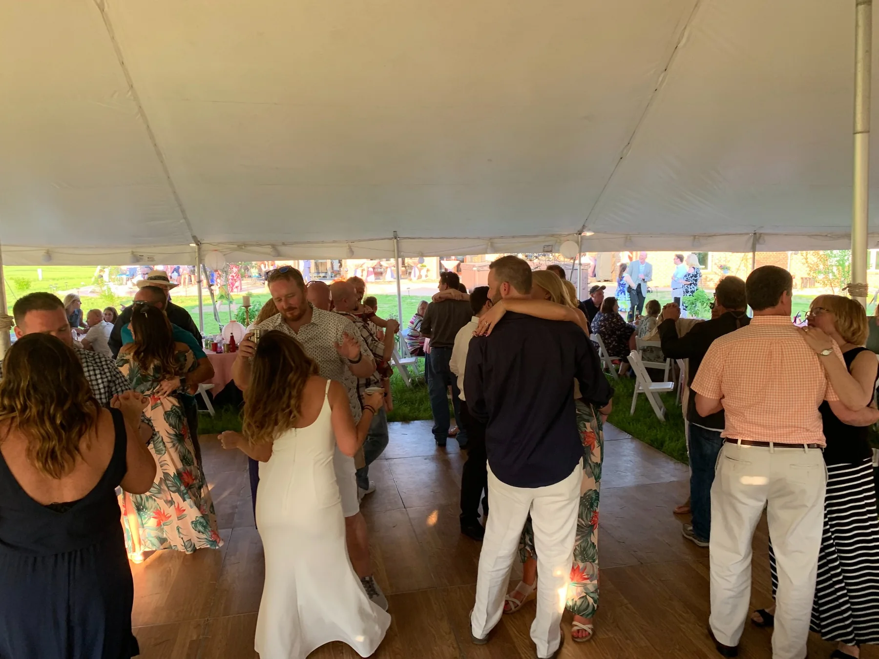 Wedding guests dancing beneath a large outdoor tent