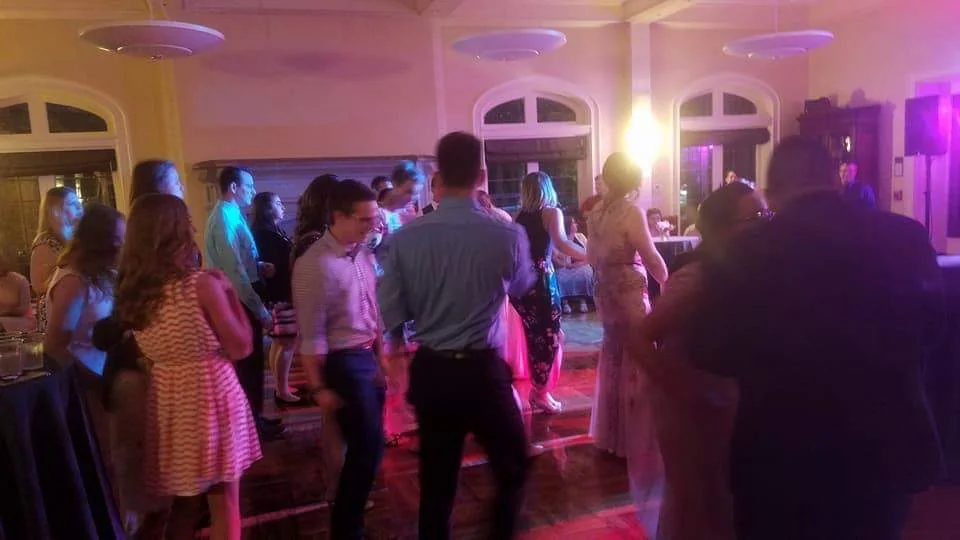 Wedding guests dancing together under colorful reception lighting